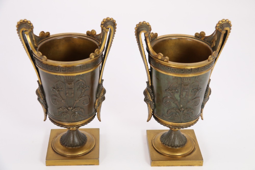 A pair of French Empire patinated and gilt bronze urns with Greek key friezes, scroll handles, and square bases. View VI