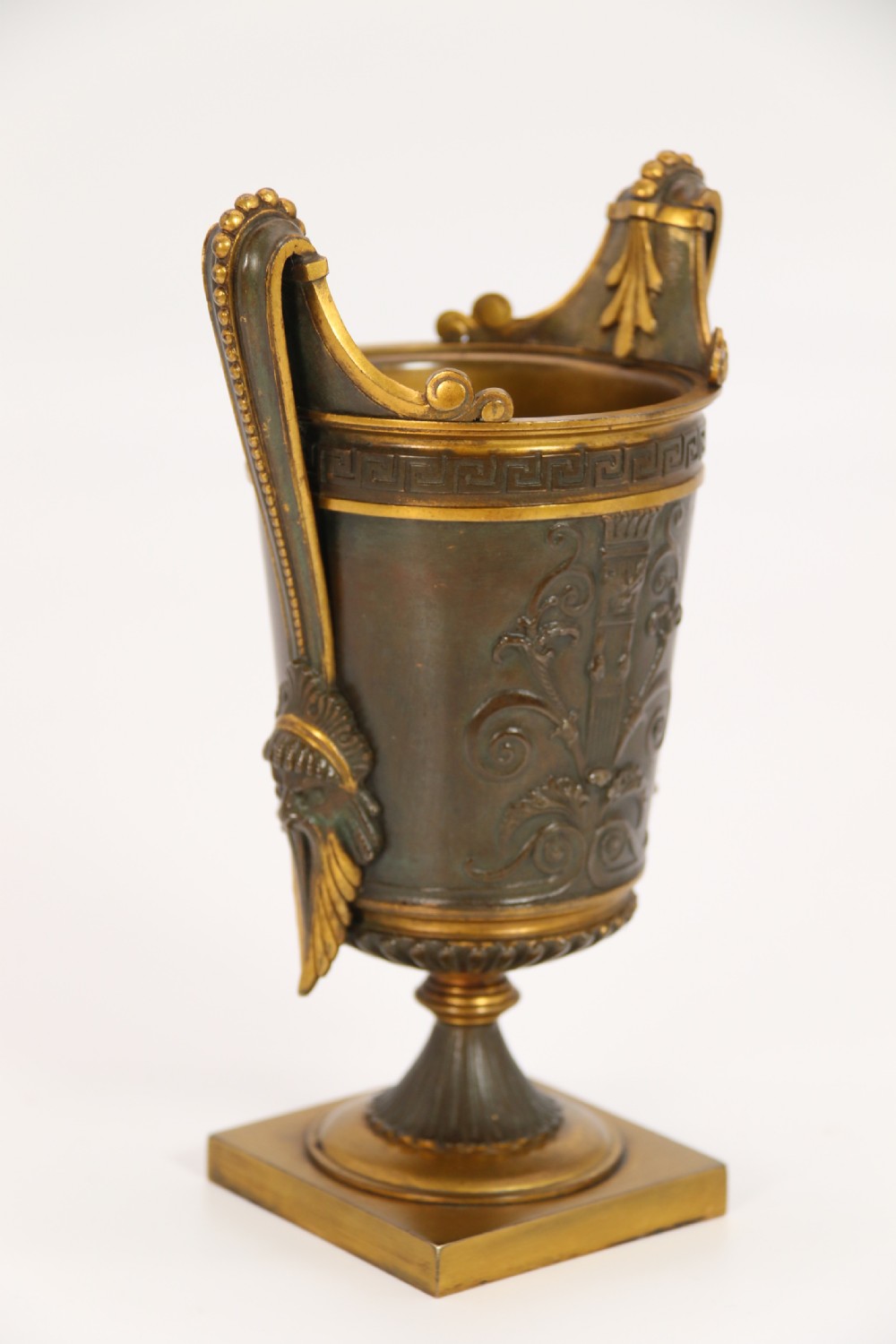 A pair of French Empire patinated and gilt bronze urns with Greek key friezes, scroll handles, and square bases. View VII