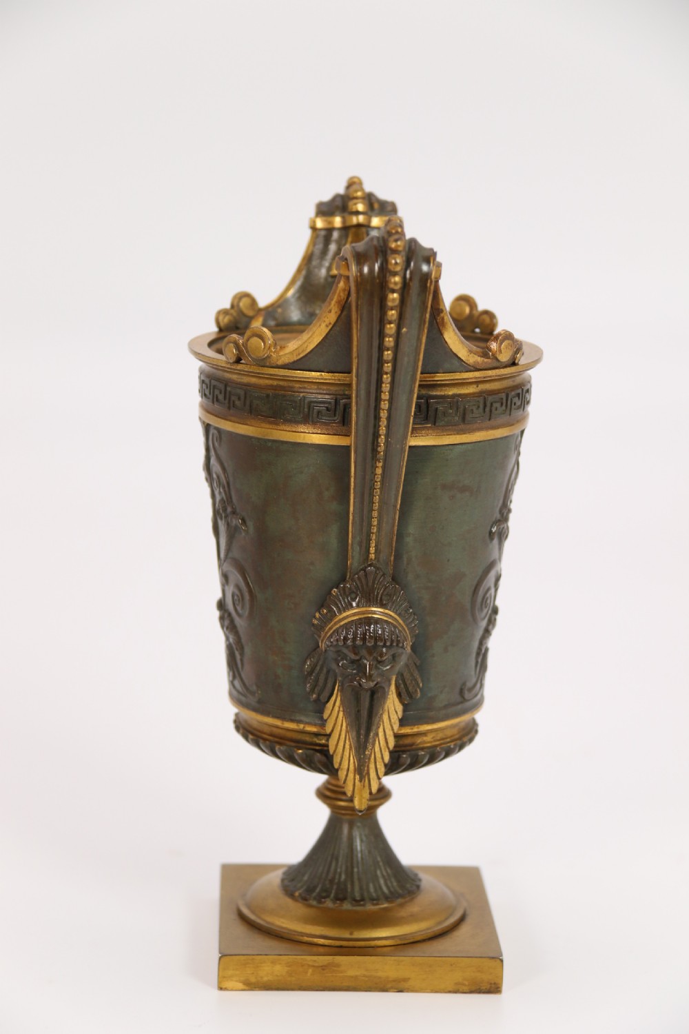 A pair of French Empire patinated and gilt bronze urns with Greek key friezes, scroll handles, and square bases. View XVII