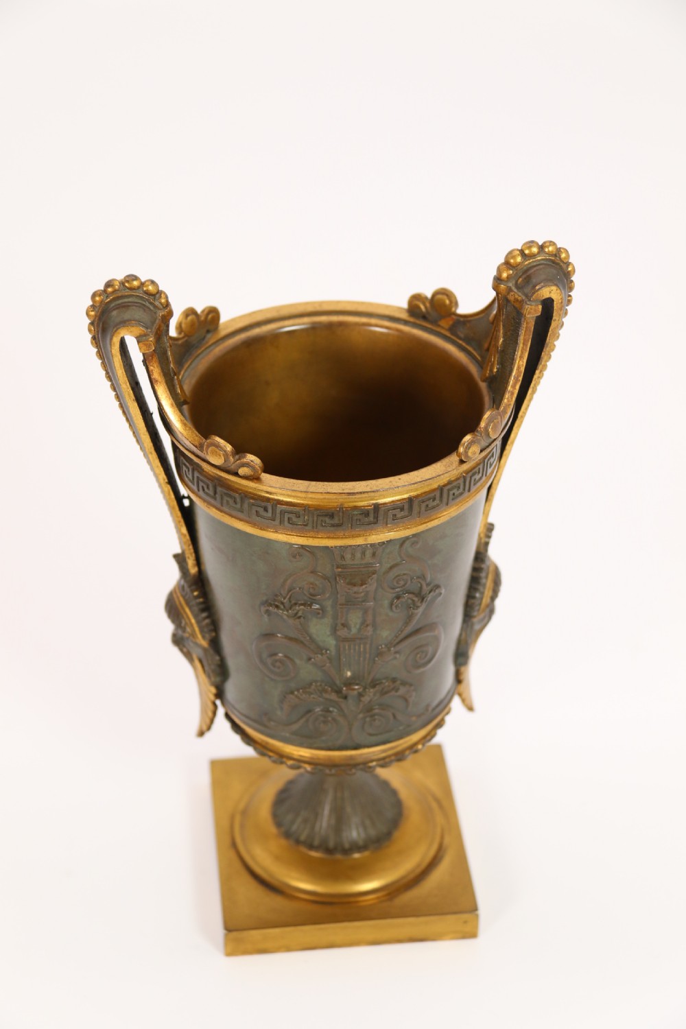 A pair of French Empire patinated and gilt bronze urns with Greek key friezes, scroll handles, and square bases. View XXI