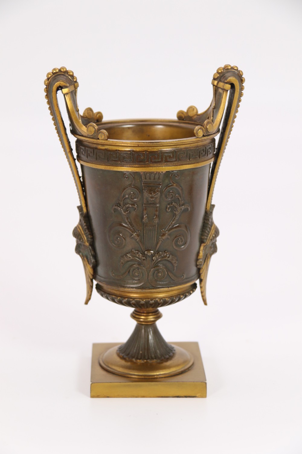 A pair of French Empire patinated and gilt bronze urns with Greek key friezes, scroll handles, and square bases. View XXIV