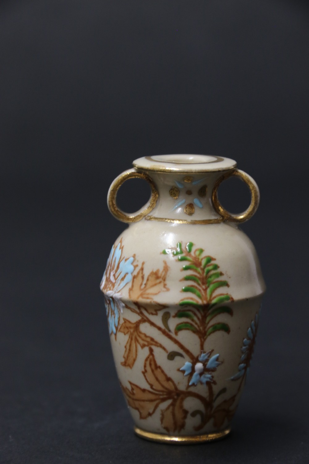A set of three antique miniature cream ceramic vases featuring hand-painted floral motifs in blue, green, and brown with gilded highlights. View XVIII