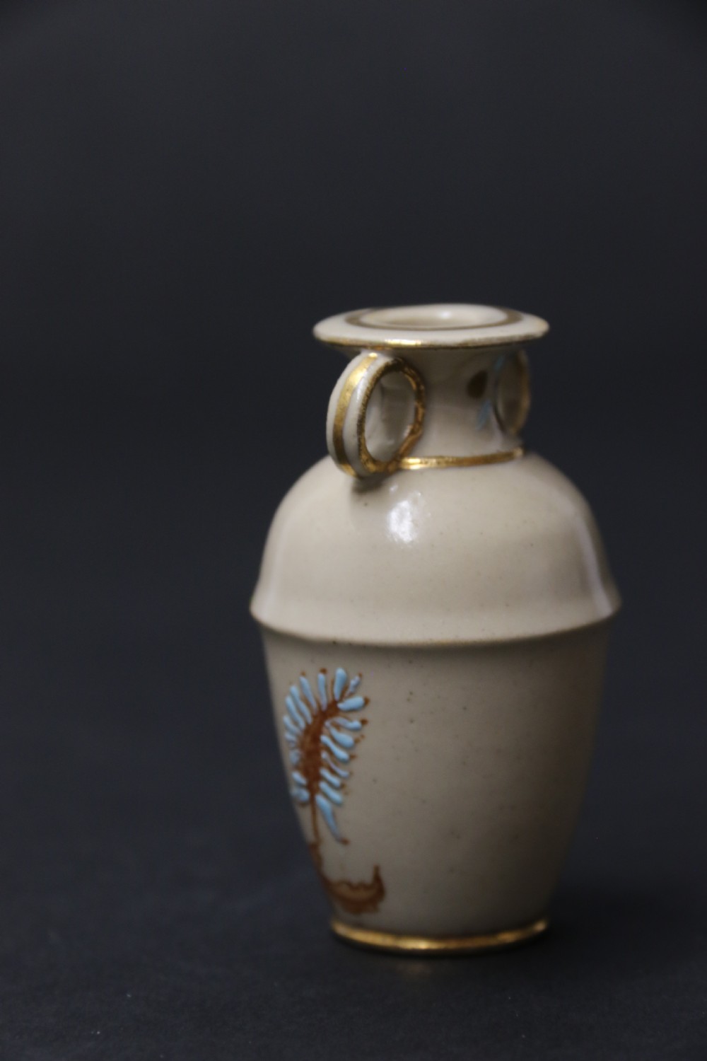 A set of three antique miniature cream ceramic vases featuring hand-painted floral motifs in blue, green, and brown with gilded highlights. View XX