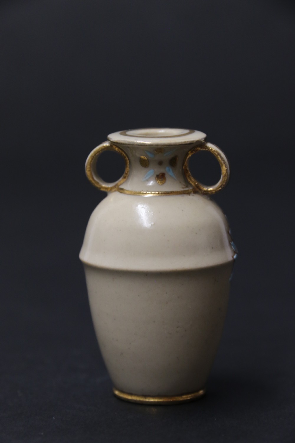 A set of three antique miniature cream ceramic vases featuring hand-painted floral motifs in blue, green, and brown with gilded highlights. View XXI