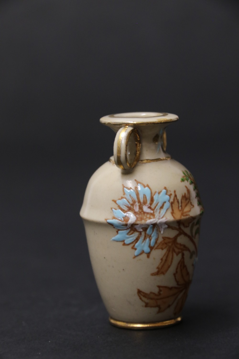 A set of three antique miniature cream ceramic vases featuring hand-painted floral motifs in blue, green, and brown with gilded highlights. View XXIII