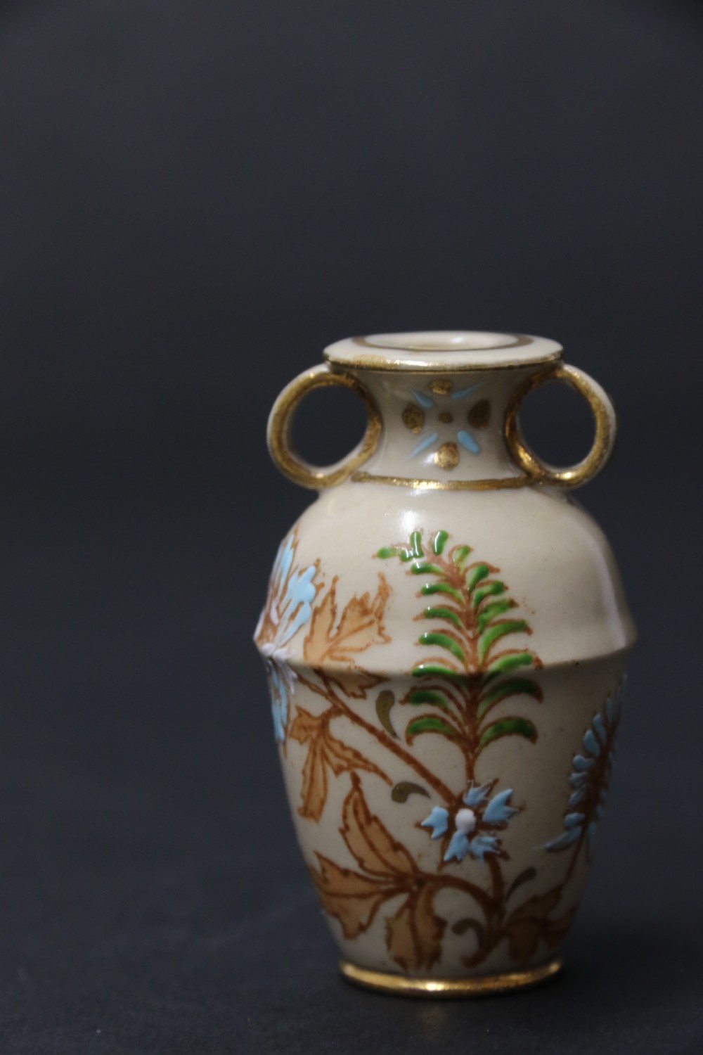 A set of three antique miniature cream ceramic vases featuring hand-painted floral motifs in blue, green, and brown with gilded highlights. View XXIV
