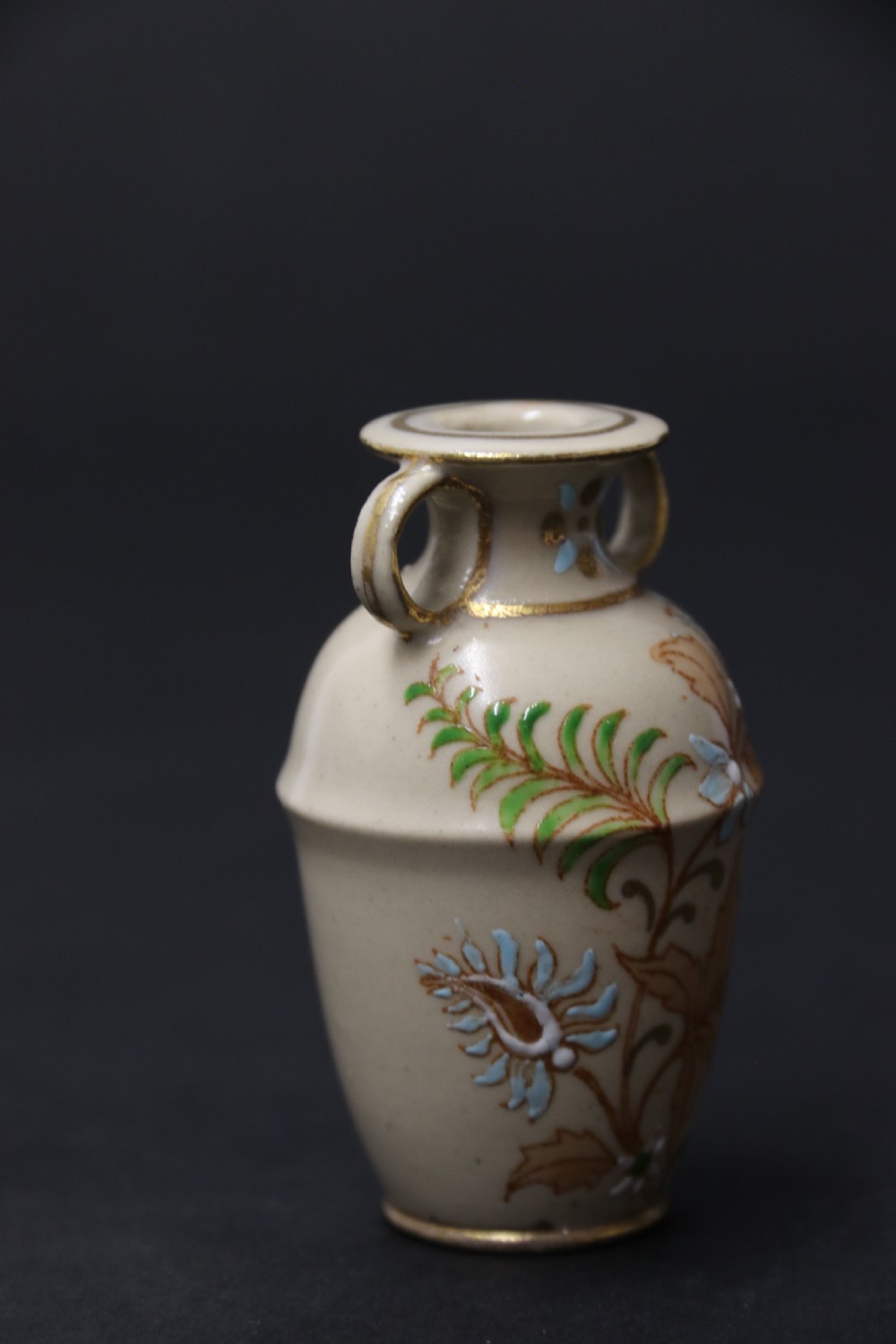 A set of three antique miniature cream ceramic vases featuring hand-painted floral motifs in blue, green, and brown with gilded highlights. View XXVII