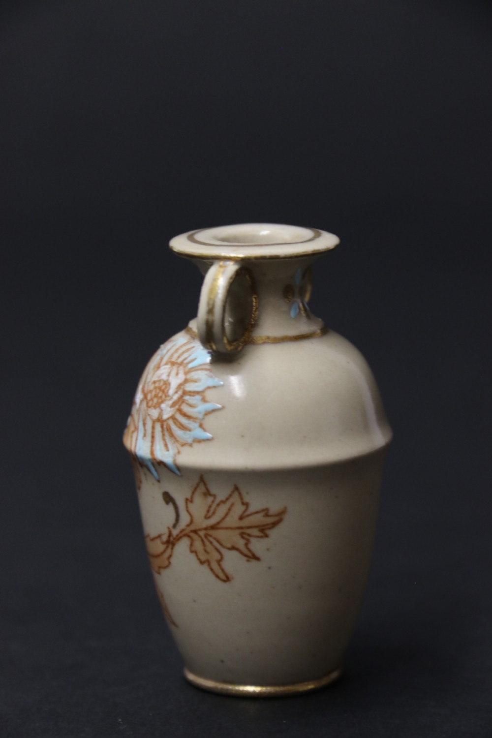 A set of three antique miniature cream ceramic vases featuring hand-painted floral motifs in blue, green, and brown with gilded highlights. View XXX
