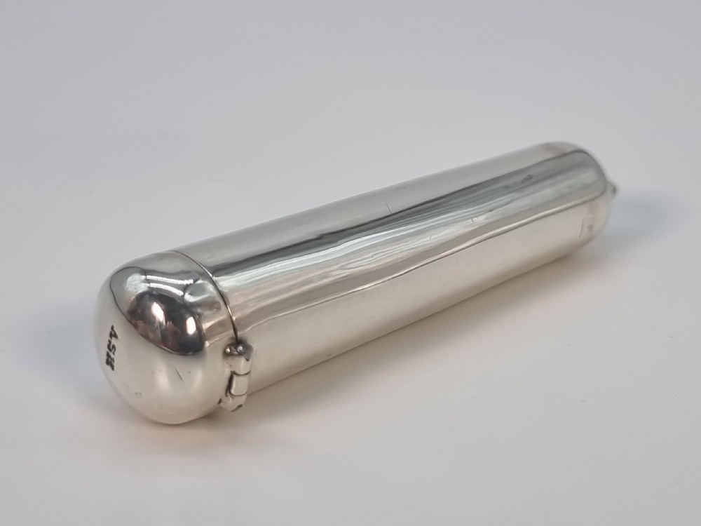 An Edwardian amber cheroot holder with a gold rim positioned next to its hallmarked sterling silver protective case. View V