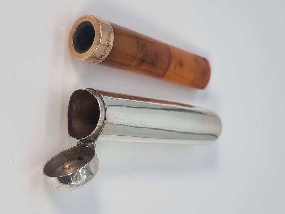 An Edwardian amber cheroot holder with a gold rim positioned next to its hallmarked sterling silver protective case. View XIII
