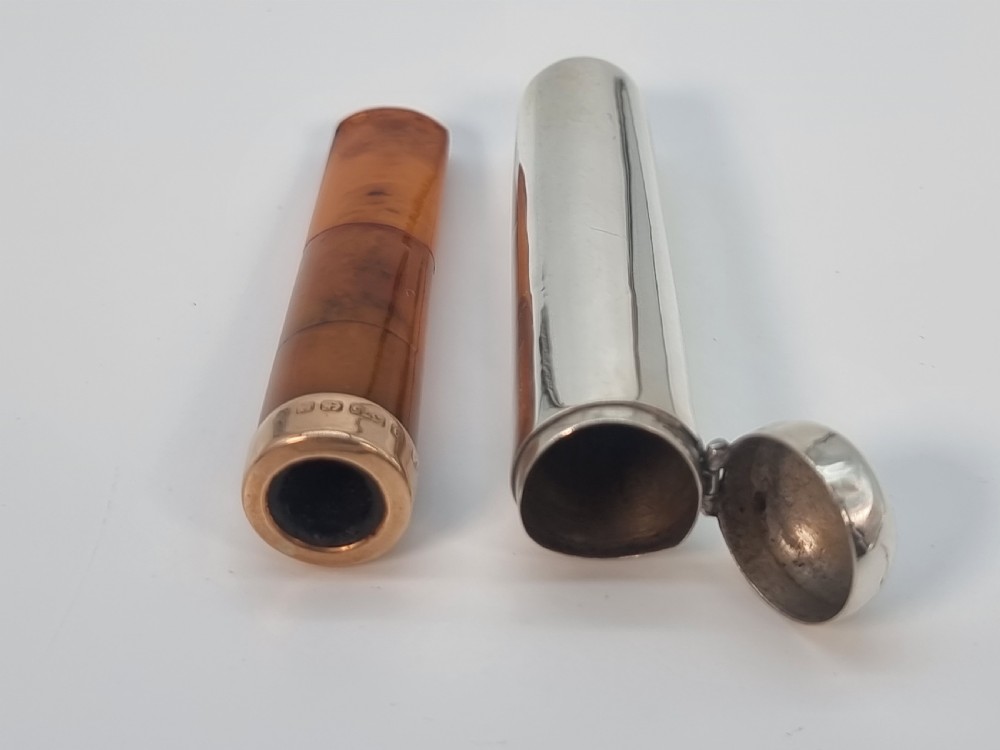 An Edwardian amber cheroot holder with a gold rim positioned next to its hallmarked sterling silver protective case. View XIV