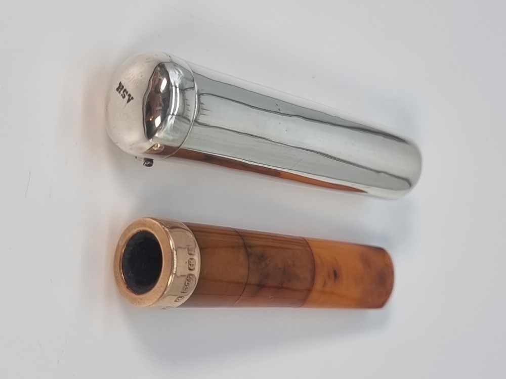 An Edwardian amber cheroot holder with a gold rim positioned next to its hallmarked sterling silver protective case. View XV