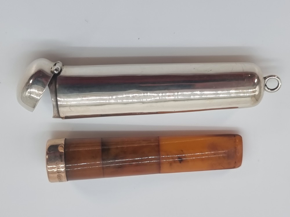 An Edwardian amber cheroot holder with a gold rim positioned next to its hallmarked sterling silver protective case. View XVII