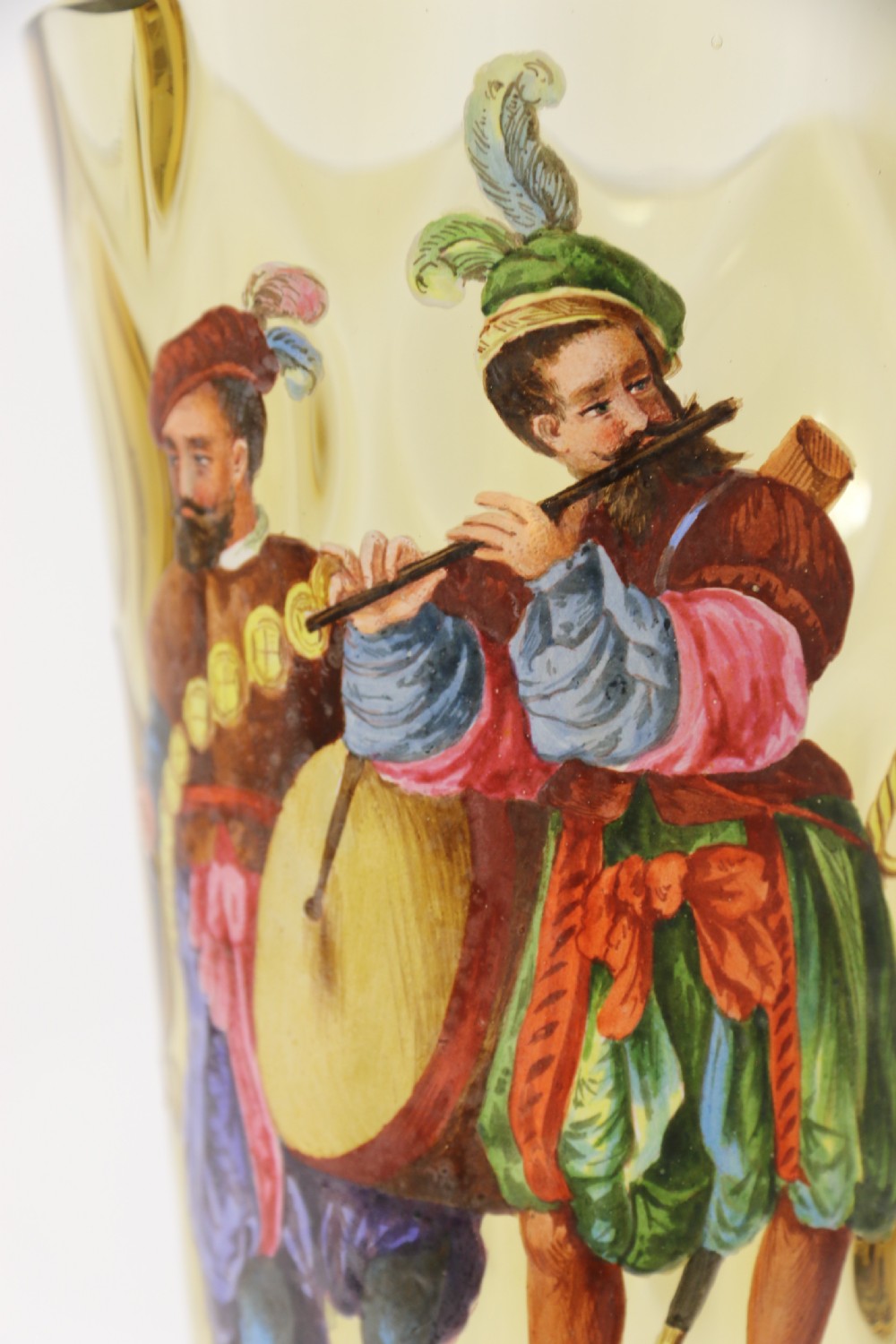 A pair of tall amber glass goblets featuring hand-painted enamelled figures of Renaissance musicians with scalloped rims and decorative knopped stems. View XIX