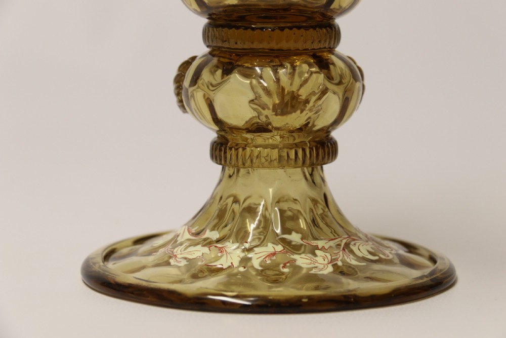 A pair of tall amber glass goblets featuring hand-painted enamelled figures of Renaissance musicians with scalloped rims and decorative knopped stems. View XXVIII