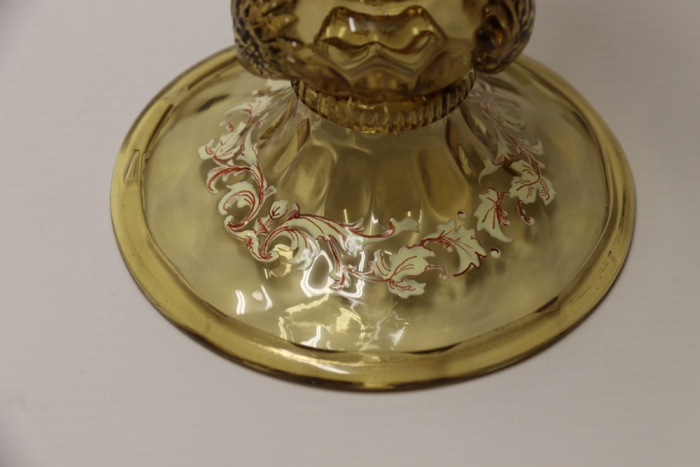 A pair of tall amber glass goblets featuring hand-painted enamelled figures of Renaissance musicians with scalloped rims and decorative knopped stems. View XXIX