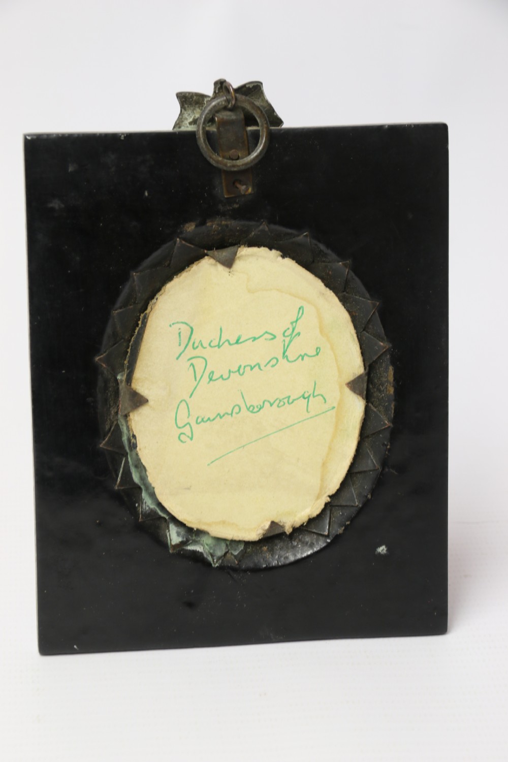 An English Regency period oval watercolour portrait miniature of a lady with dark hair, set in a rectangular black ebonised frame with a brass leaf hanger mount. View VI