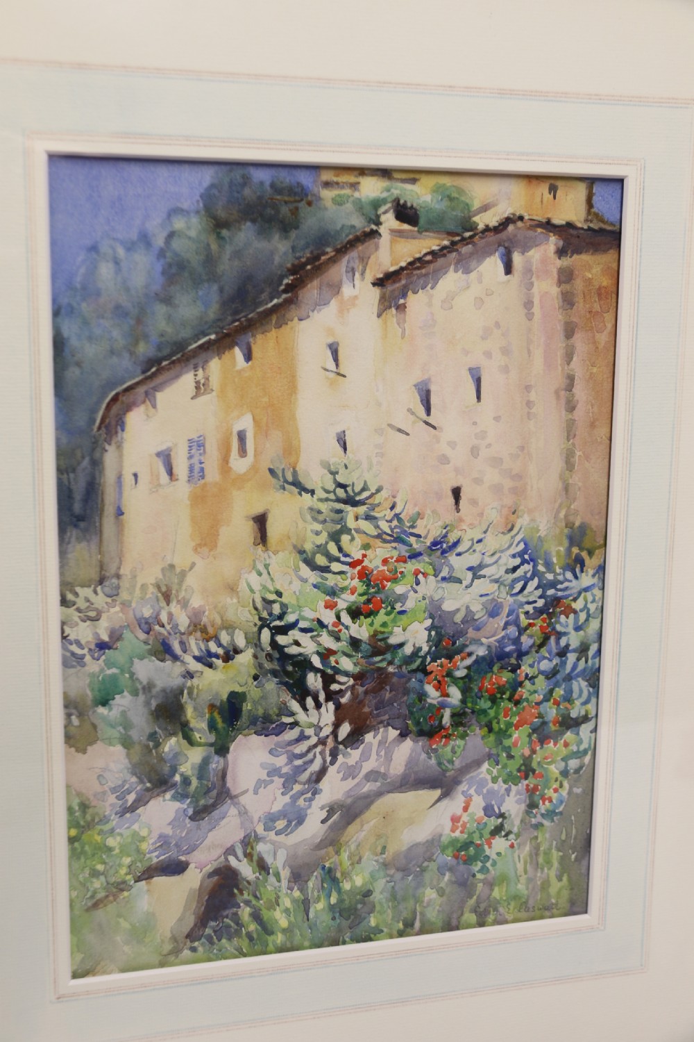 A framed 1920s watercolour painting depicting a sunlit Mediterranean building behind foliage, set within an ornate gilded frame. View II