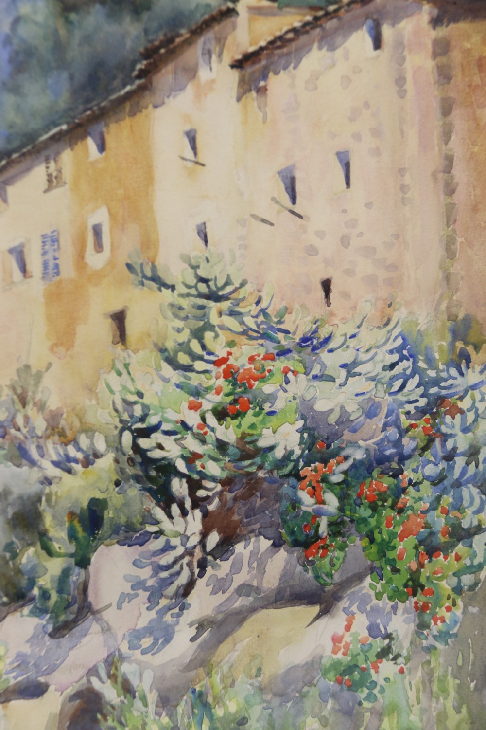 A framed 1920s watercolour painting depicting a sunlit Mediterranean building behind foliage, set within an ornate gilded frame. View VII