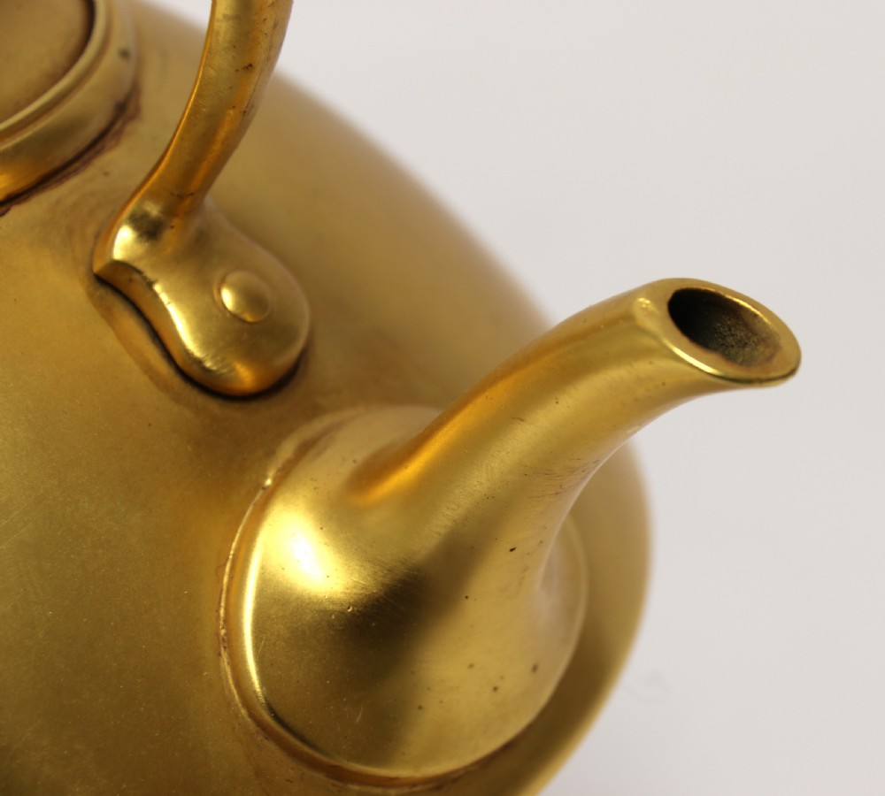 A late 19th-century Aesthetic Movement brass spirit kettle with a cane-wrapped handle, resting on a tripod brass stand with an alcohol burner. View VI