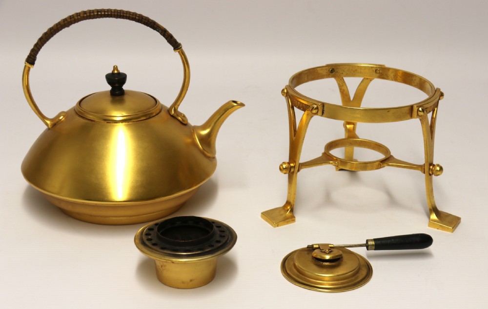 A late 19th-century Aesthetic Movement brass spirit kettle with a cane-wrapped handle, resting on a tripod brass stand with an alcohol burner. View IX