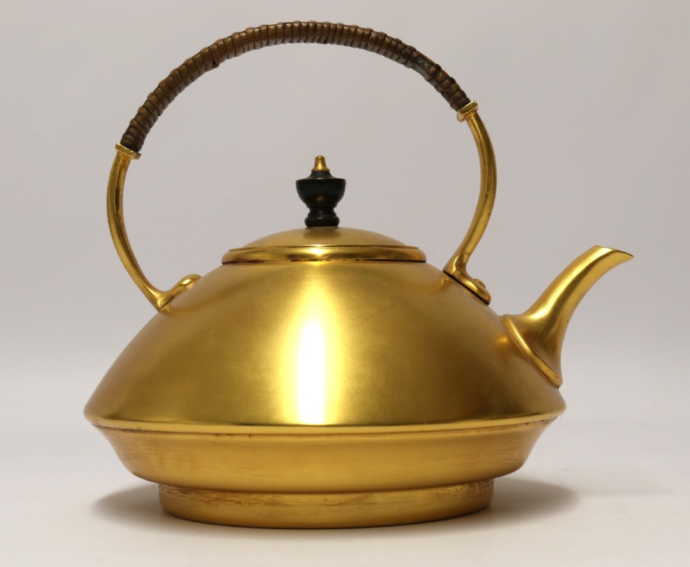 A late 19th-century Aesthetic Movement brass spirit kettle with a cane-wrapped handle, resting on a tripod brass stand with an alcohol burner. View XV