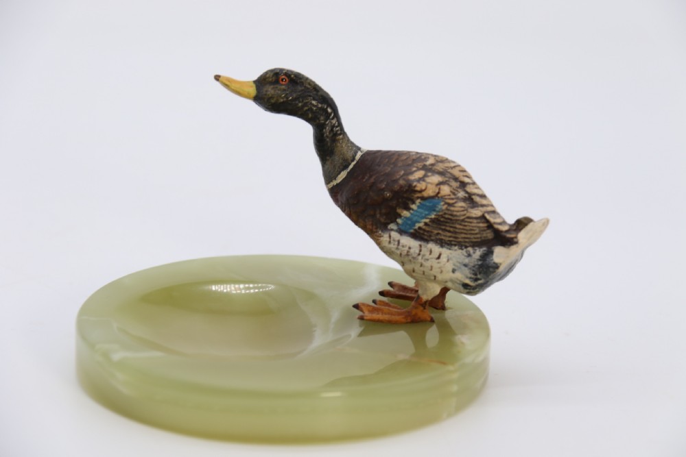 A cold painted bronze study of a mallard duck standing on the rim of a dished, circular green onyx base. View III