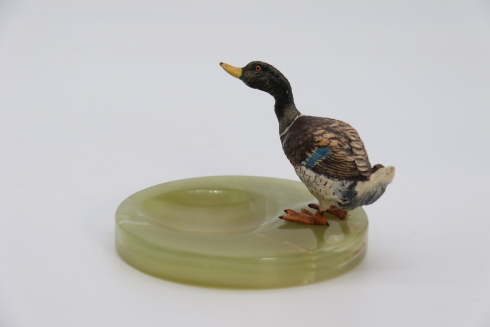 A cold painted bronze study of a mallard duck standing on the rim of a dished, circular green onyx base. View V