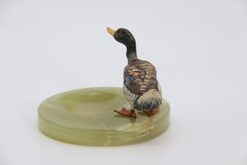 A cold painted bronze study of a mallard duck standing on the rim of a dished, circular green onyx base. View VI
