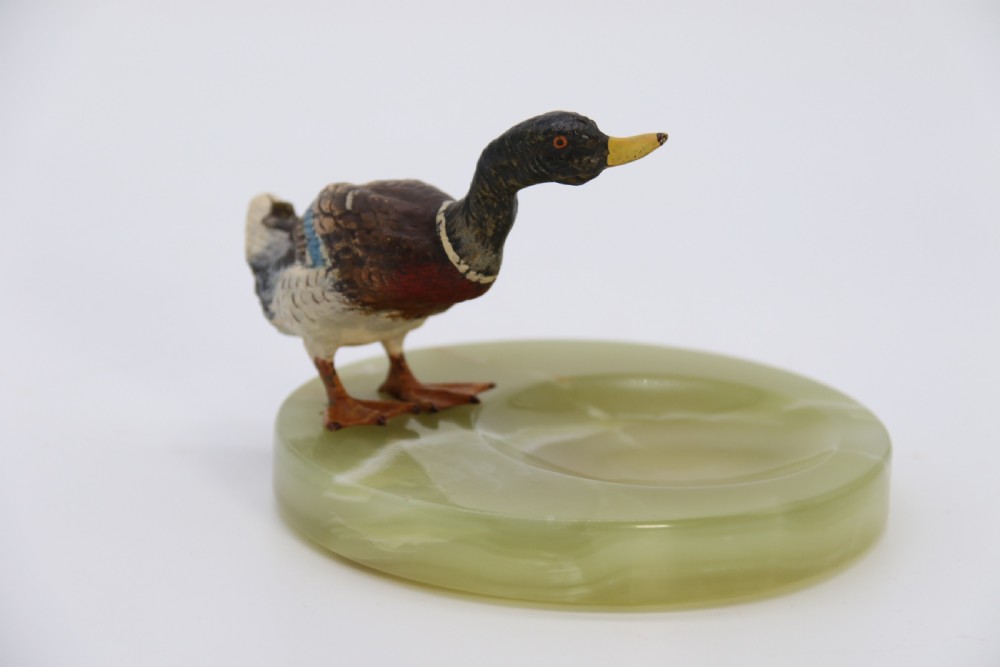 A cold painted bronze study of a mallard duck standing on the rim of a dished, circular green onyx base. View IX