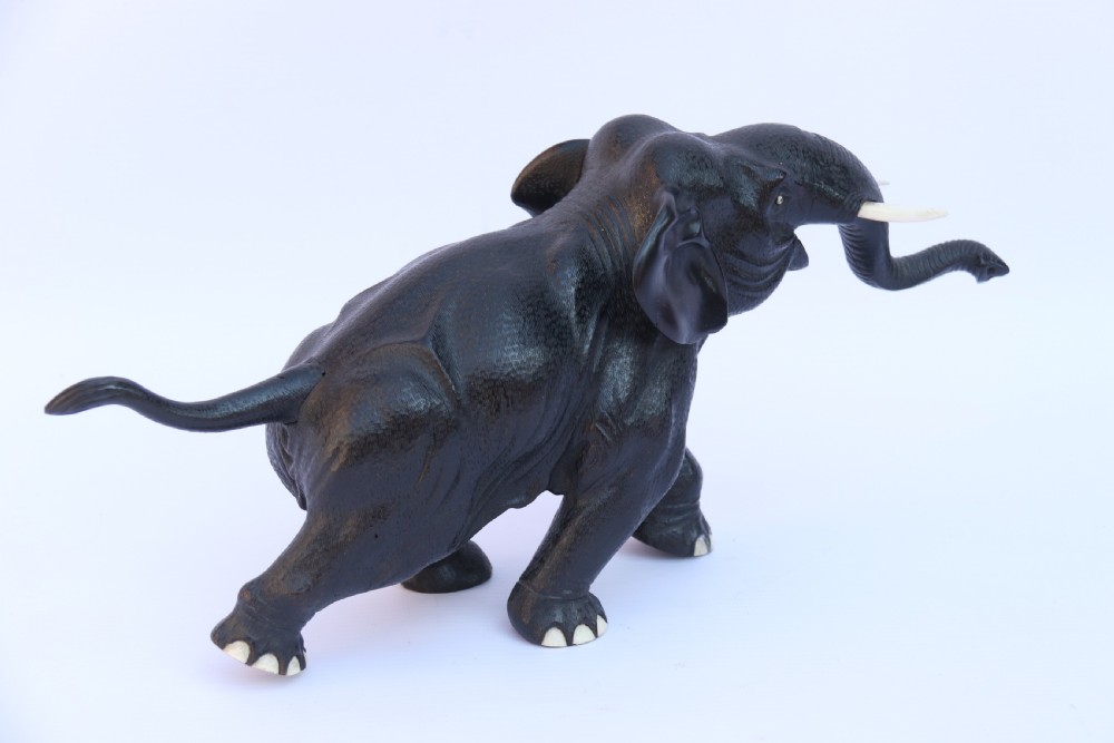 A late 19th-century hand-carved black ebony elephant sculpture shown in a striding pose with inlaid bone tusks and toenails. View VII