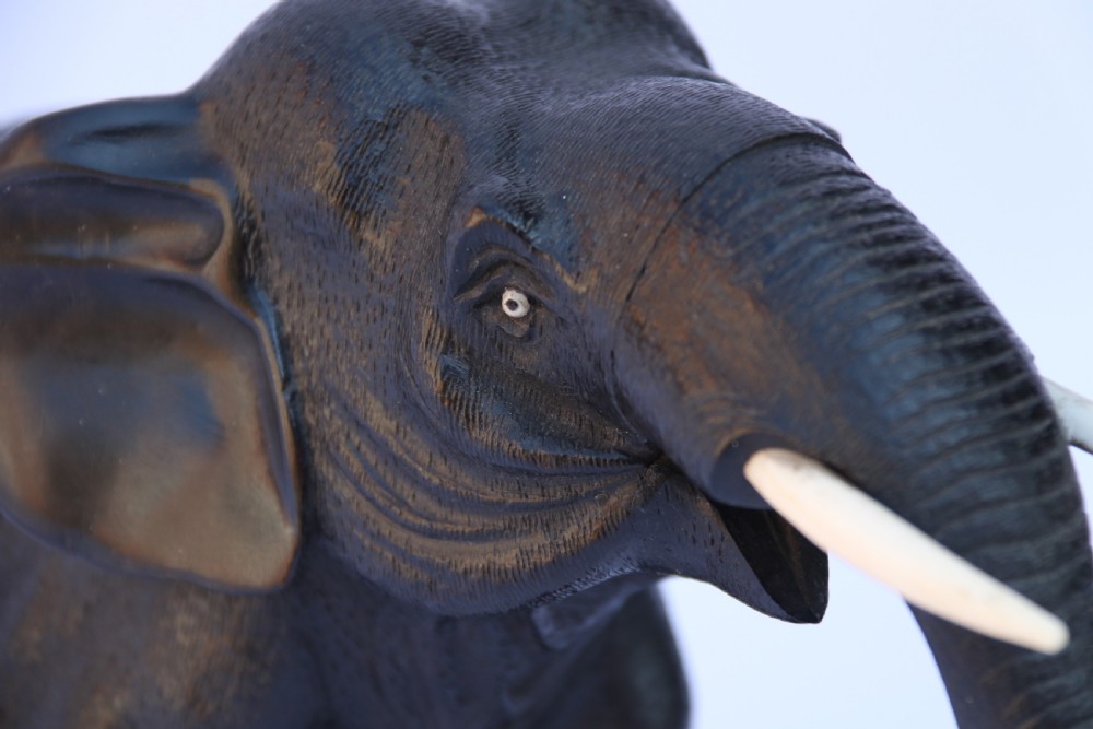 A late 19th-century hand-carved black ebony elephant sculpture shown in a striding pose with inlaid bone tusks and toenails. View XI