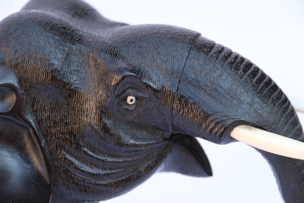 A late 19th-century hand-carved black ebony elephant sculpture shown in a striding pose with inlaid bone tusks and toenails. View XII