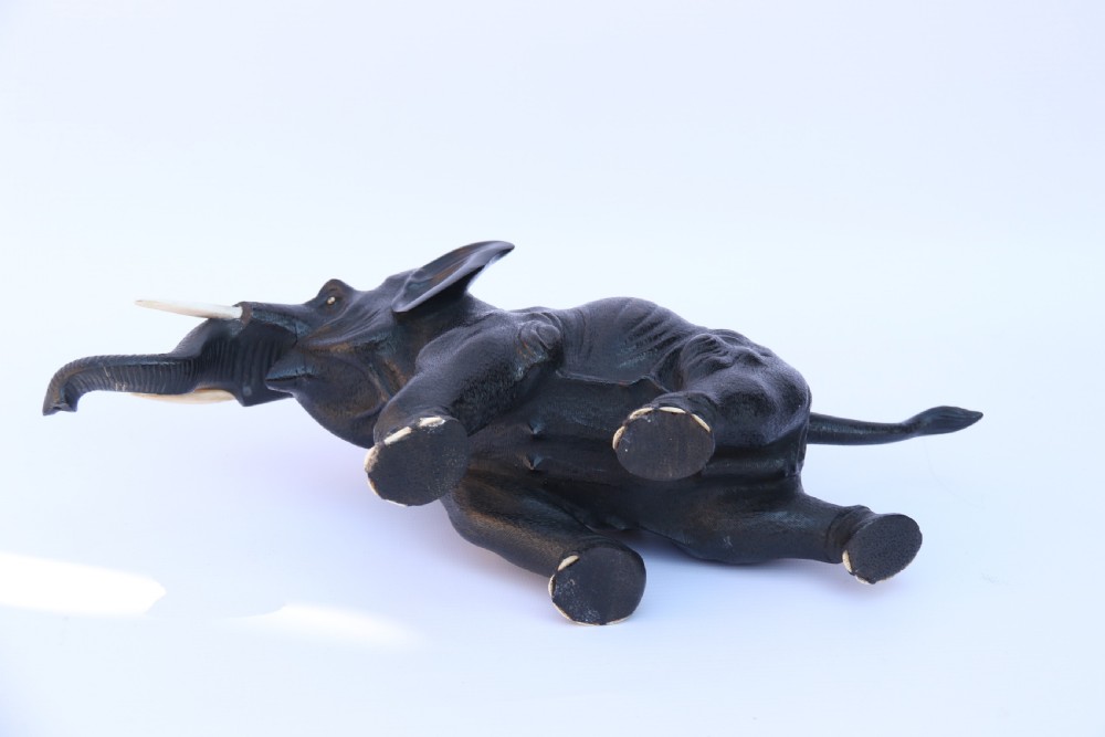 A late 19th-century hand-carved black ebony elephant sculpture shown in a striding pose with inlaid bone tusks and toenails. View XIII