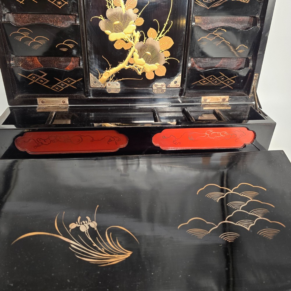 A black lacquer Japanese writing box decorated with detailed gold botanical and bird illustrations, featuring a hinged lid opening to internal correspondence slots. View XXV