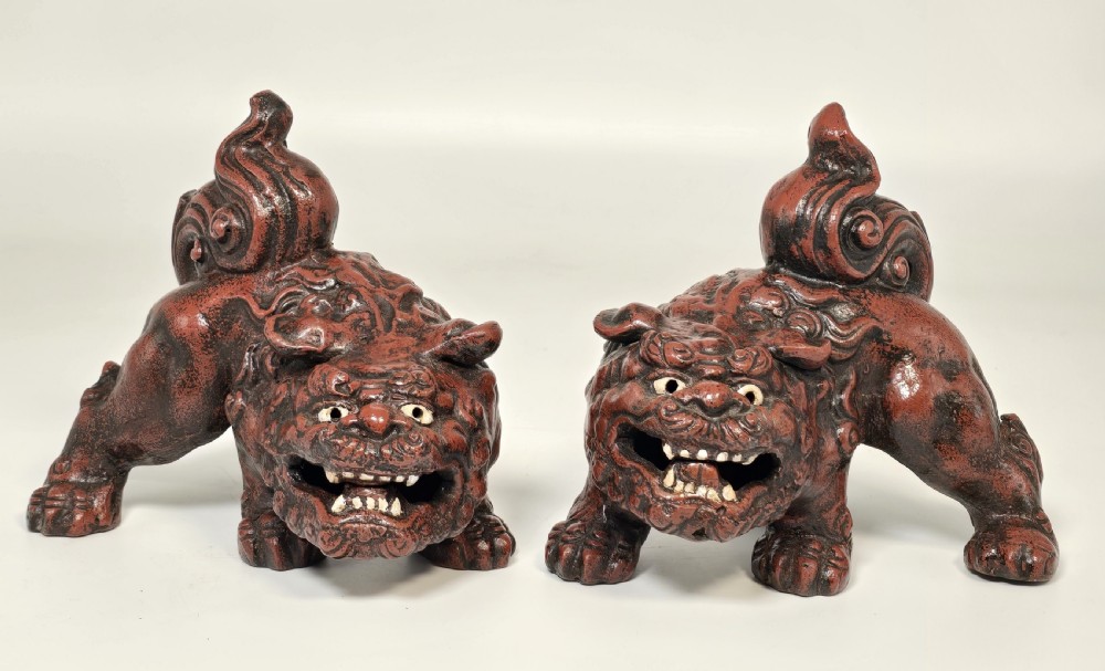 A pair of reddish-brown cast iron Chinese guardian lion figures featuring raised tails and open mouths displaying white painted teeth. View III