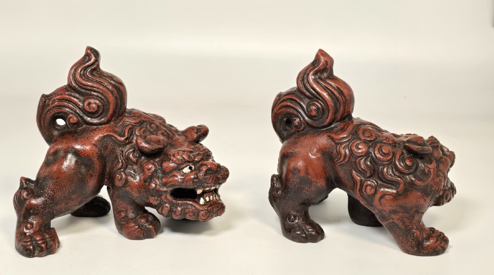 A pair of reddish-brown cast iron Chinese guardian lion figures featuring raised tails and open mouths displaying white painted teeth. View VII