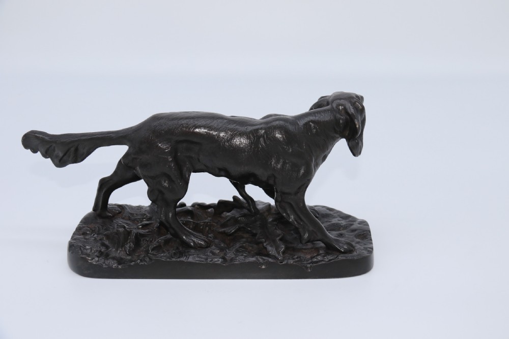 A black cast iron sculpture depicting a hunting dog walking across a naturalistic earth base. View XIII