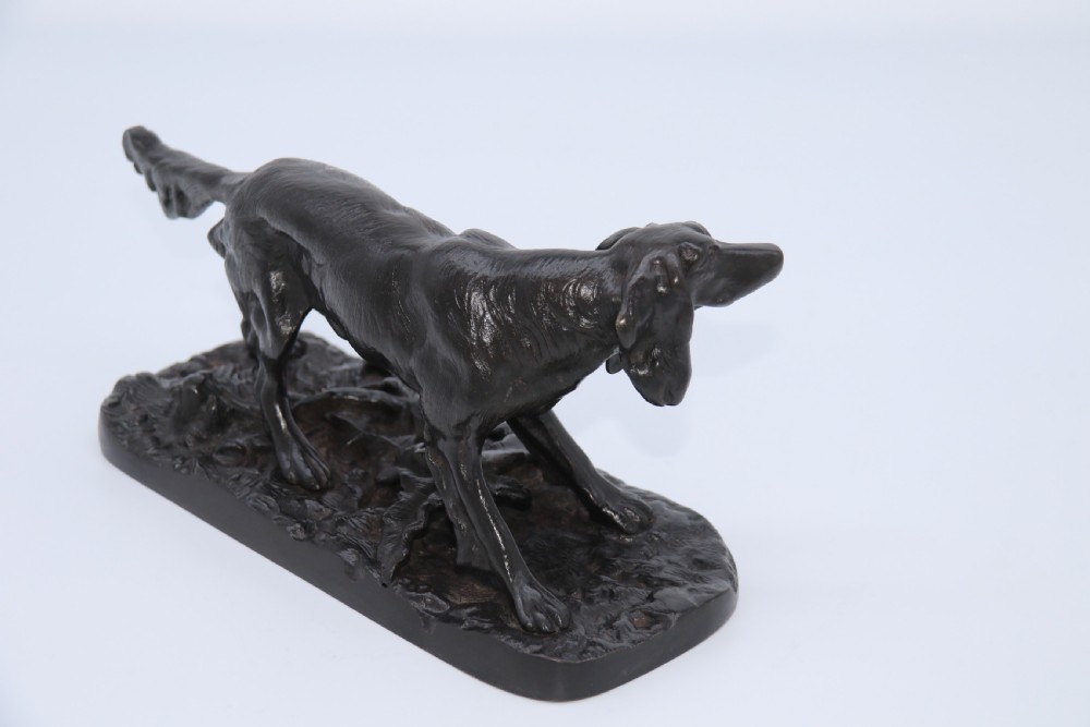 A black cast iron sculpture depicting a hunting dog walking across a naturalistic earth base. View XIV