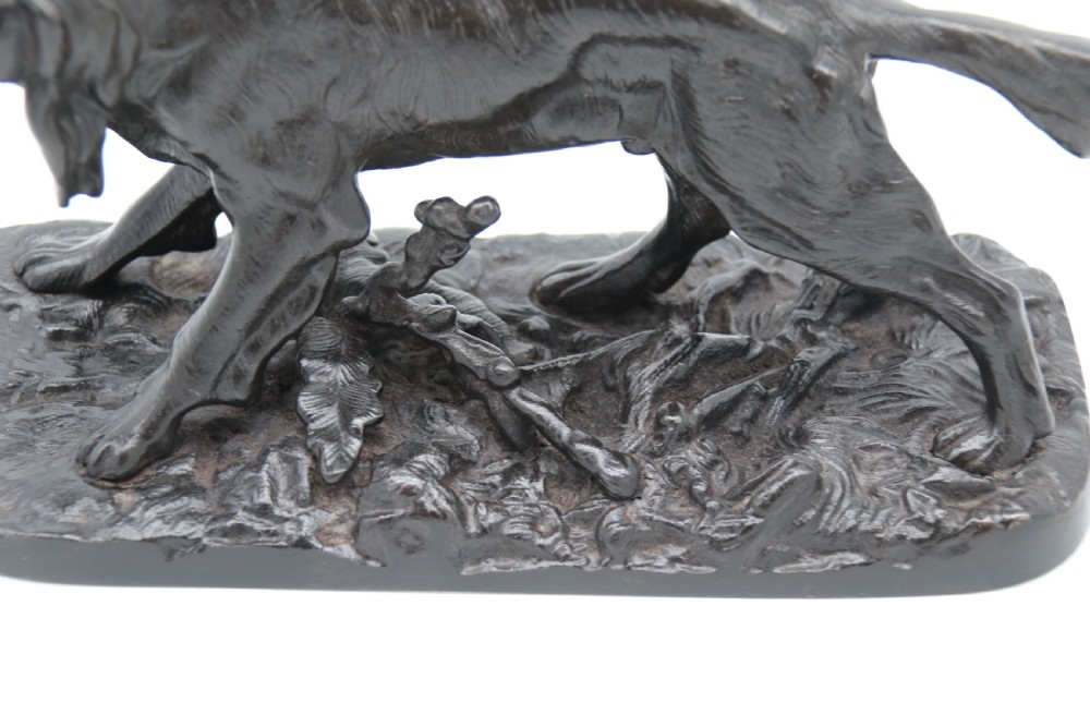 A black cast iron sculpture depicting a hunting dog walking across a naturalistic earth base. View XV