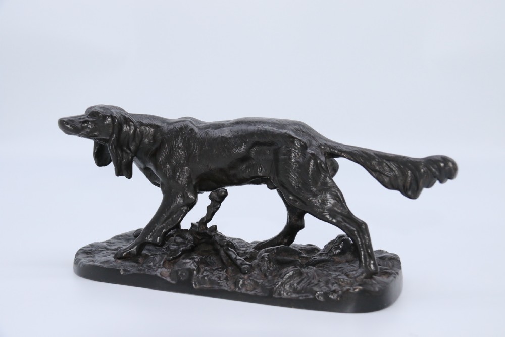 A black cast iron sculpture depicting a hunting dog walking across a naturalistic earth base. View XVII