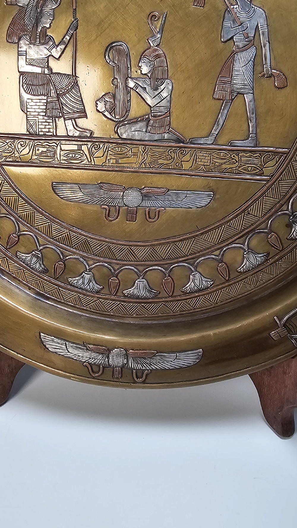 A circular brass charger featuring inlaid silver and copper depiction of Ancient Egyptian figures, hieroglyphs, and winged sun disc motifs. View IV