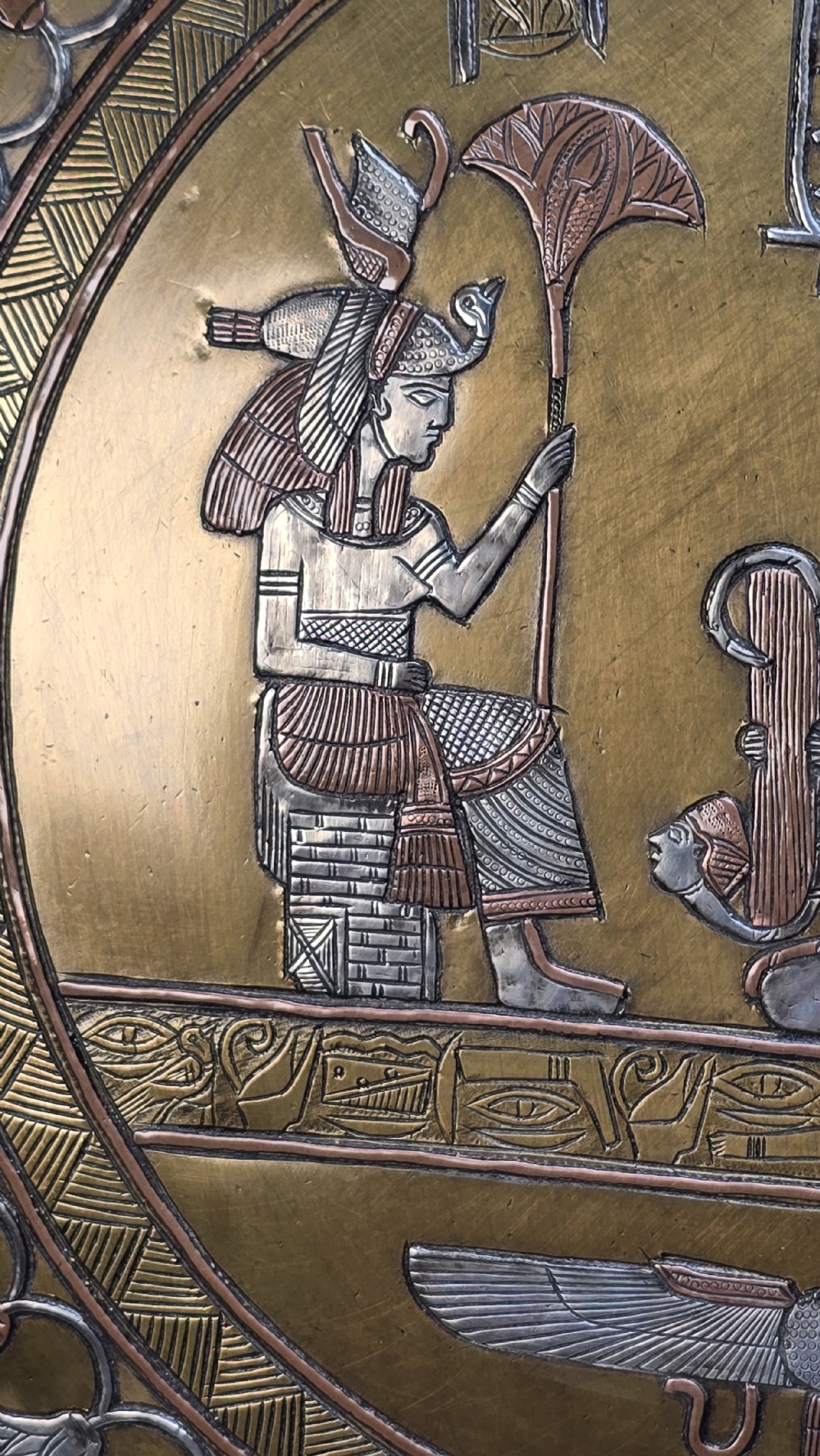 A circular brass charger featuring inlaid silver and copper depiction of Ancient Egyptian figures, hieroglyphs, and winged sun disc motifs. View XVI