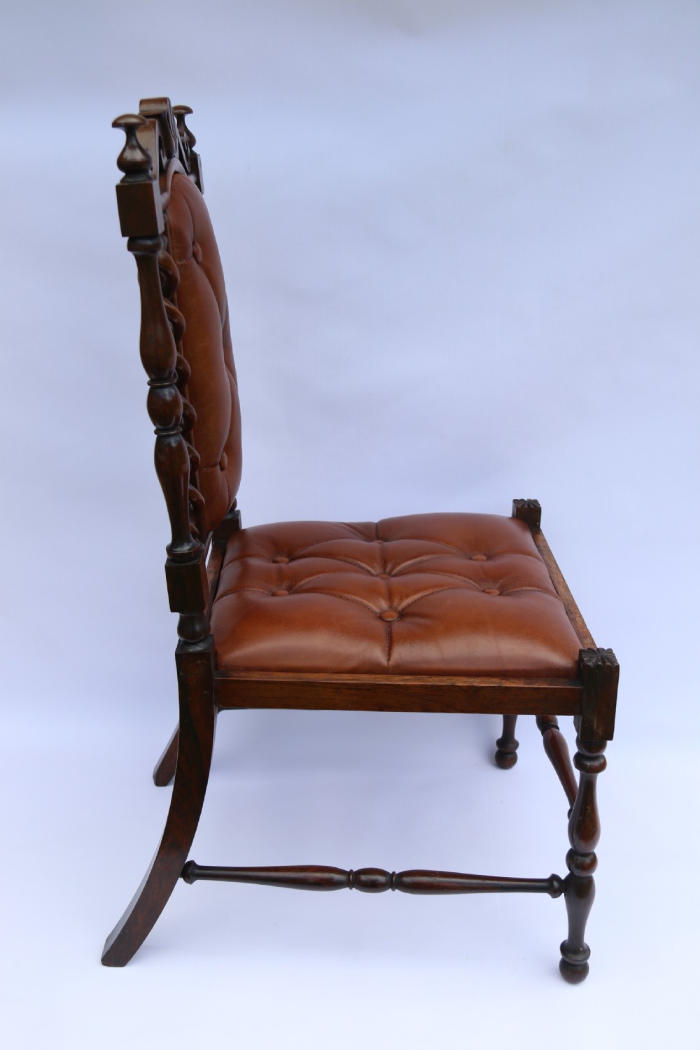 An early Victorian childs chair crafted from carved rosewood with barley twist columns, turned legs, and button-tufted brown leather upholstery on the seat and backrest. View III