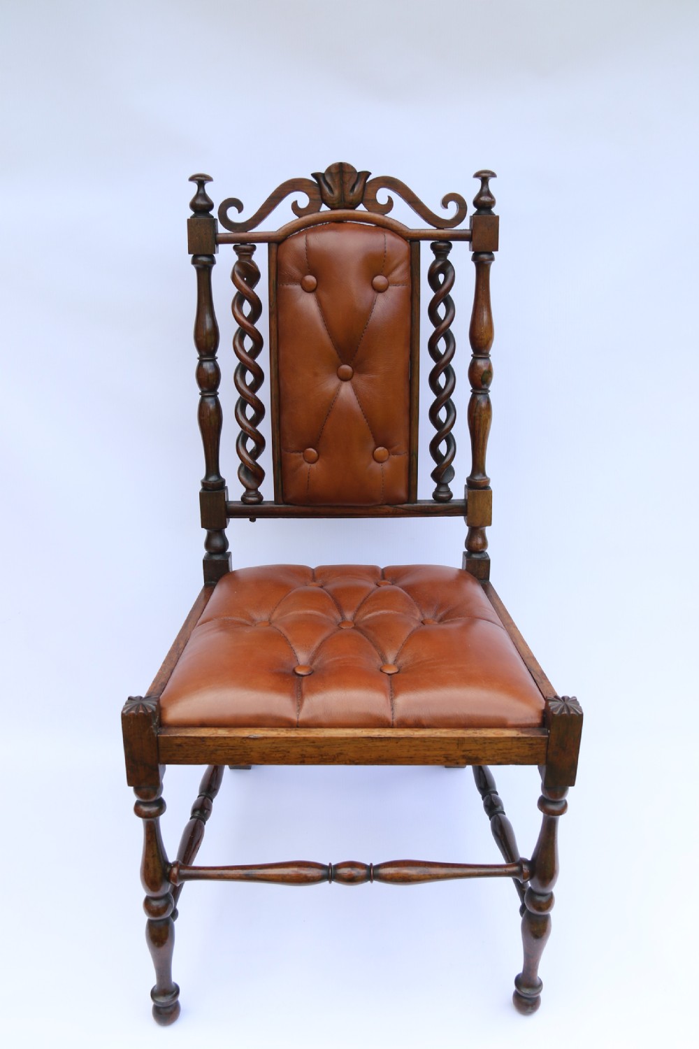 An early Victorian childs chair crafted from carved rosewood with barley twist columns, turned legs, and button-tufted brown leather upholstery on the seat and backrest. View VII