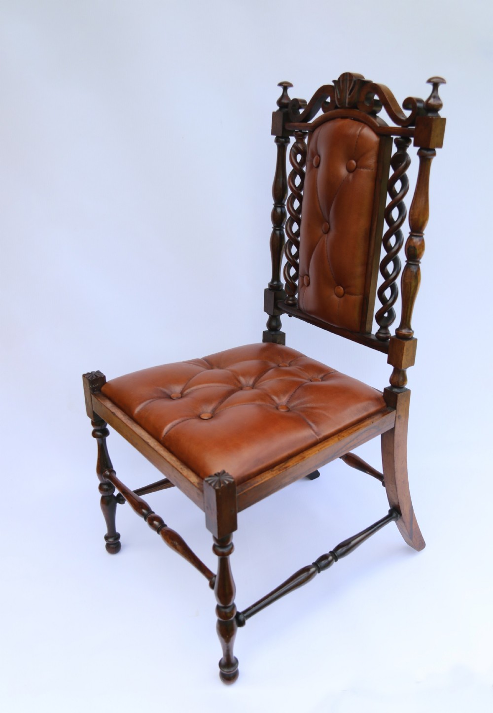 An early Victorian childs chair crafted from carved rosewood with barley twist columns, turned legs, and button-tufted brown leather upholstery on the seat and backrest. View VIII