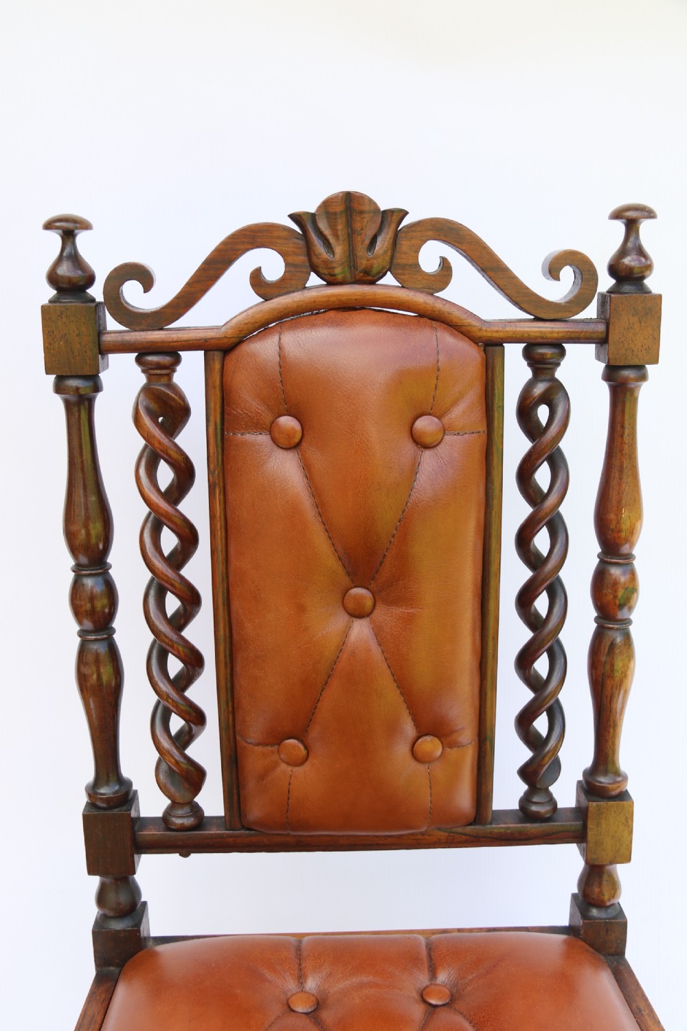 An early Victorian childs chair crafted from carved rosewood with barley twist columns, turned legs, and button-tufted brown leather upholstery on the seat and backrest. View XI