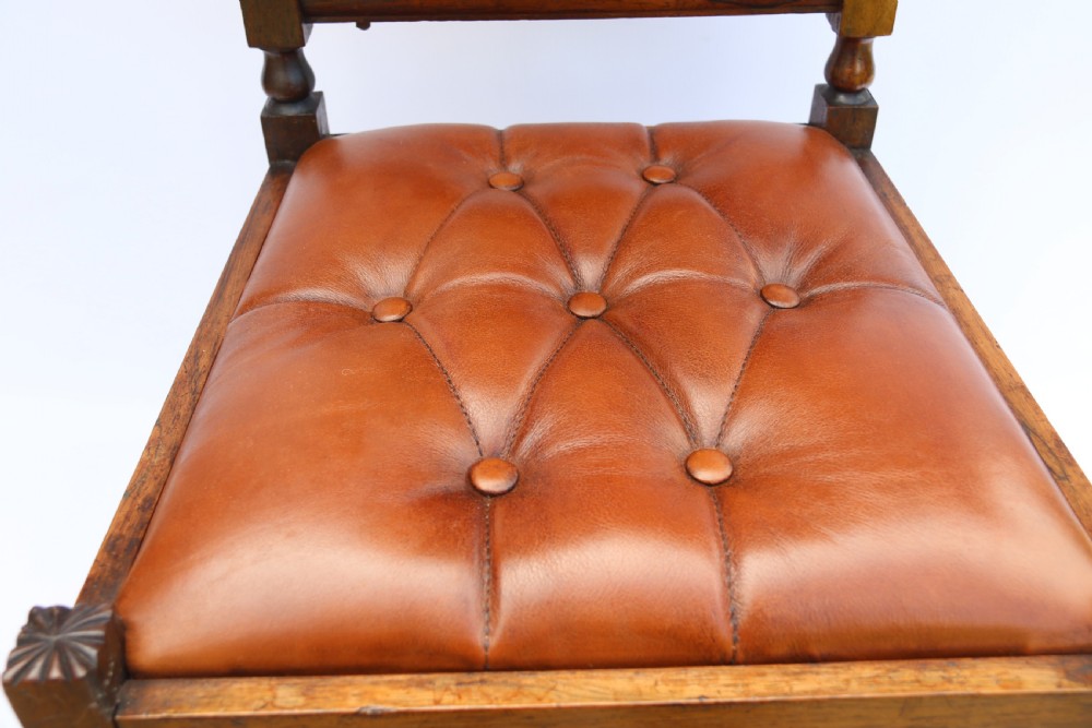 An early Victorian childs chair crafted from carved rosewood with barley twist columns, turned legs, and button-tufted brown leather upholstery on the seat and backrest. View XII