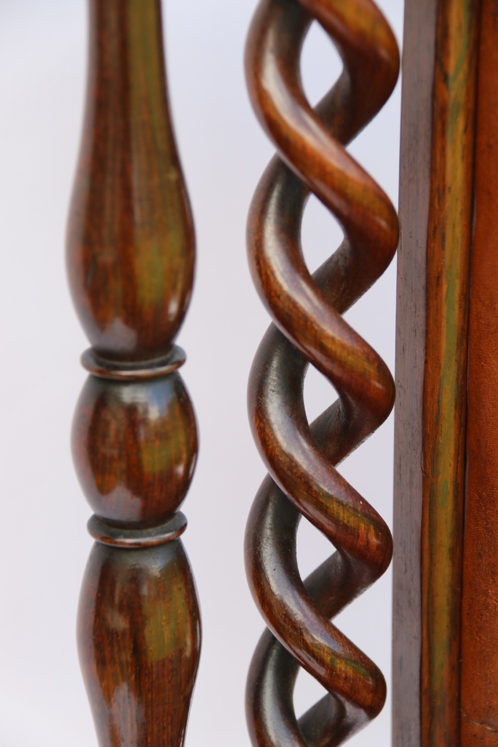 An early Victorian childs chair crafted from carved rosewood with barley twist columns, turned legs, and button-tufted brown leather upholstery on the seat and backrest. View XIII