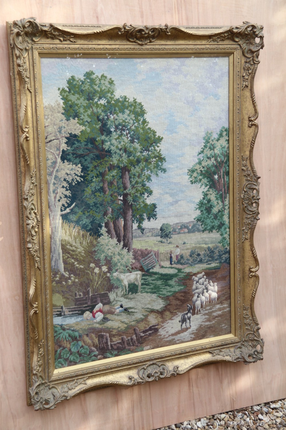 A large framed woolwork needlepoint tapestry depicting a pastoral landscape scene enclosed in a heavily ornamented giltwood frame. View V